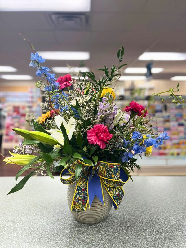 Colorful mixed flower arrangement in a vase with a decorative bow.