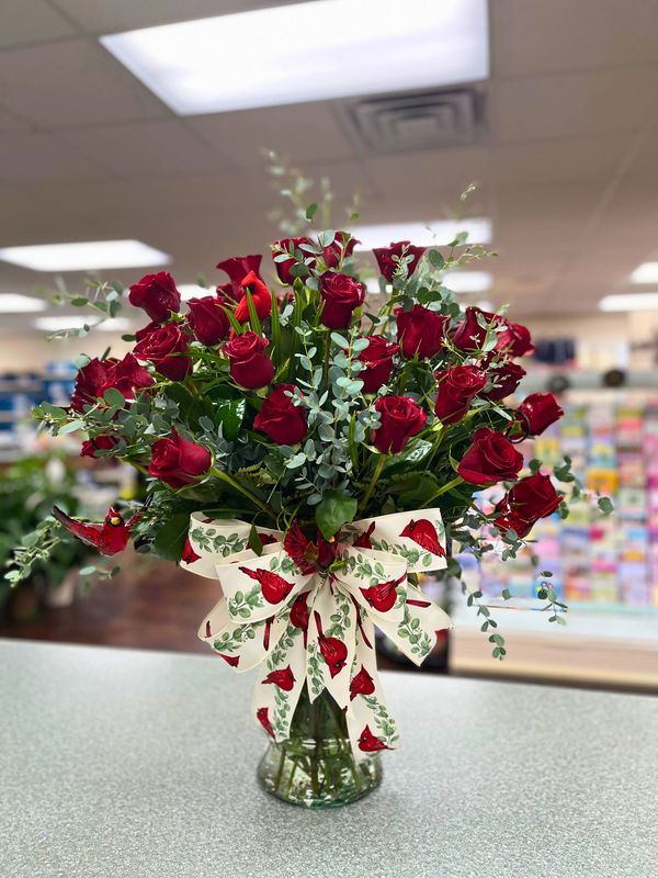 A bouquet of red roses in a vase with a decorative ribbon.