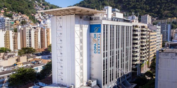 Hospital Copa D'Or em área urbana com morros ao fundo.