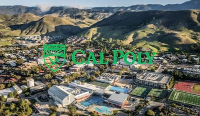 Aerial view of Cal Poly campus nestled in green hills under a clear sky.
