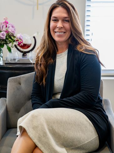Smiling woman sitting comfortably in a modern living room with flowers and decorative items.