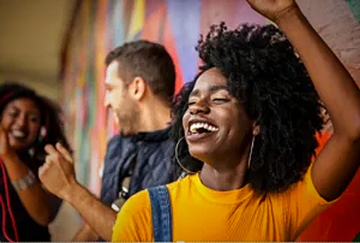 Friends joyfully dancing and laughing together outdoors.