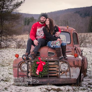 Couple on 1949 Ford truck in snow with Christmas theme.
