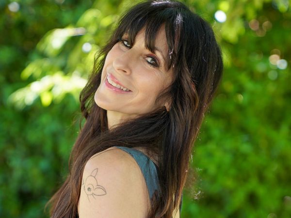 Woman with long hair smiling outdoors.