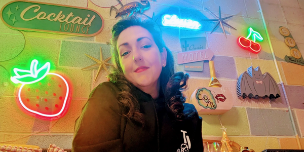 A badass bitch in her element. She has fair skin, salt & pepper hair, red lipstick, & black eyeliner