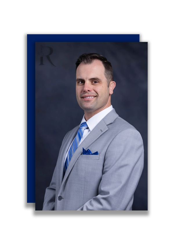 Professional man in a light gray suit with a blue tie and pocket square.