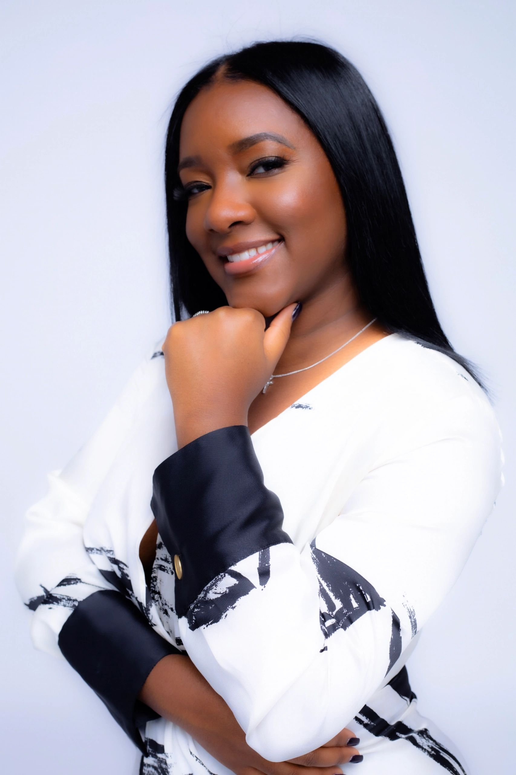 Confident woman smiling with hand on chin.