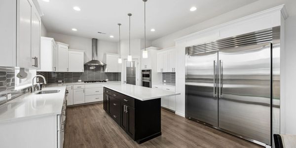 Modern kitchen with white cabinets, dark island, and stainless steel appliances.