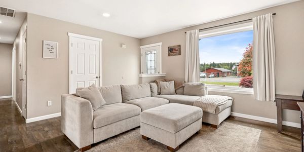 Cozy beige sectional sofa with ottoman in a bright living room with a large window.