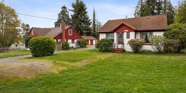 Two houses with red and white exteriors surrounded by greenery on a clear day.