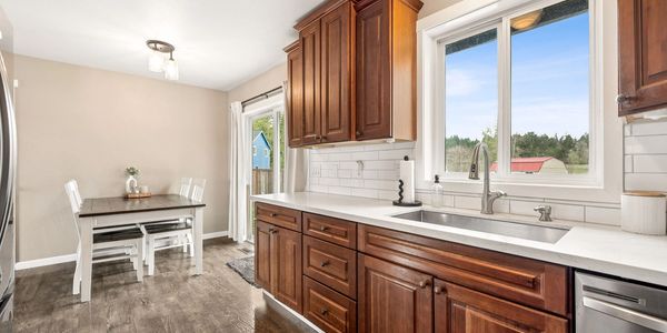 Bright kitchen with wooden cabinets and a dining area near a sliding glass door.