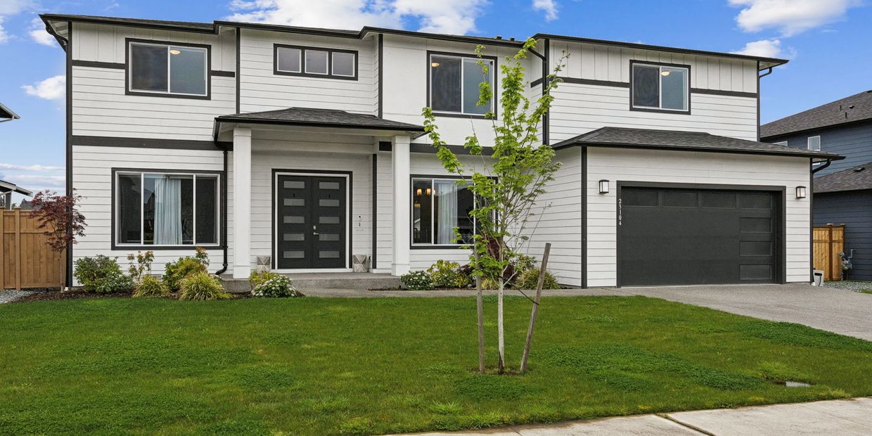 Modern two-story house with black trim and a spacious lawn.
