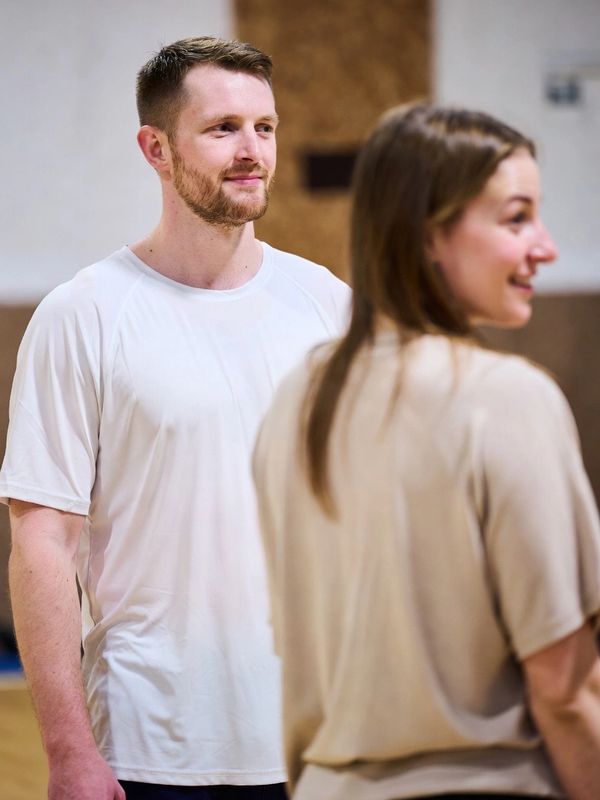 Two people engaged in a casual conversation indoors, smiling and relaxed.