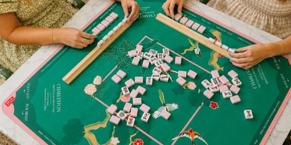 Two people playing a game with tiles on a green mat.