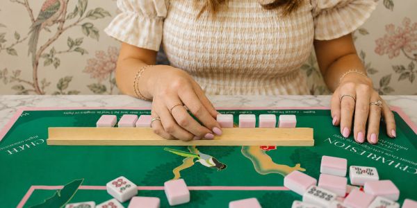 Person arranging mahjong tiles on a table.