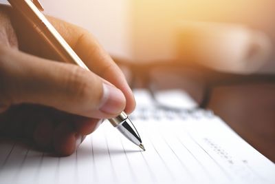 Close up picture of a person writing in a notebook. 