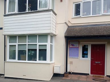 Entrance of a beige building with a red door and windows.