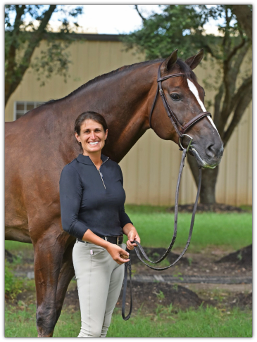 Smiling woman standing beside a brown horse with a white blaze on its face.