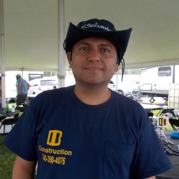 Man wearing a cowboy hat and a construction company t-shirt.