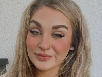 A smiling woman with blonde hair and nose piercings.