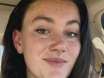 Close-up of a woman with freckles and a septum piercing.