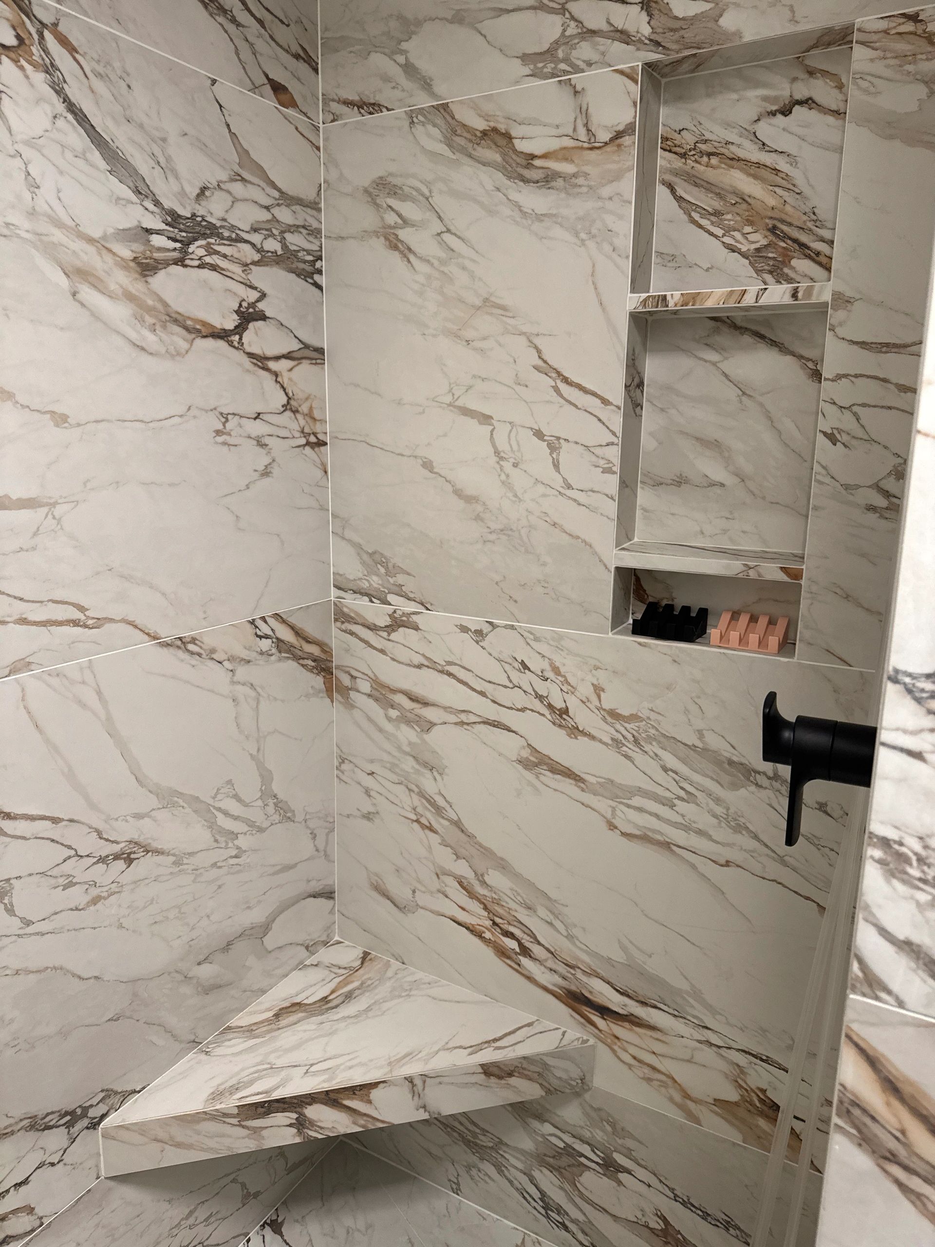 Marble shower corner with built-in shelves and bench.