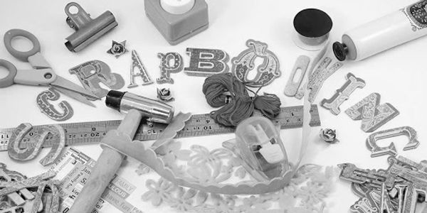 Crafting tools and decorative letters spelling "SCRAPBOOKING" on a workspace.