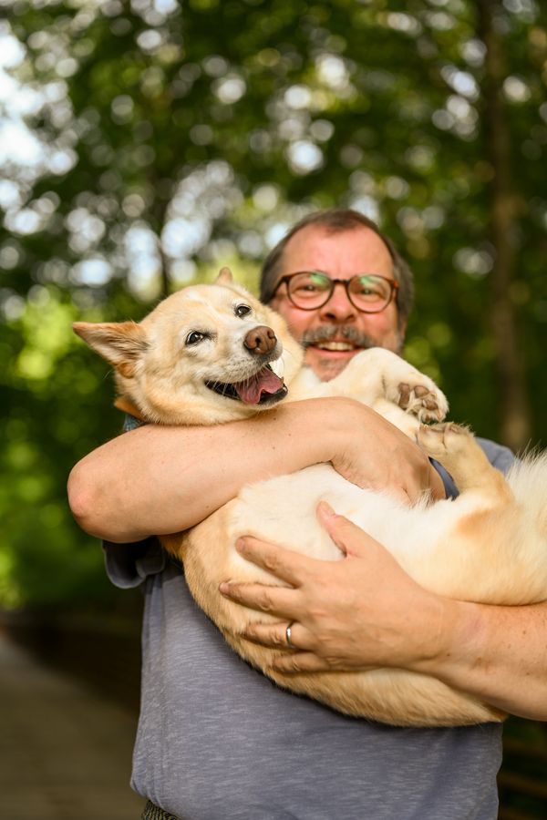 Man happily holding a joyful dog in his arms outdoors.