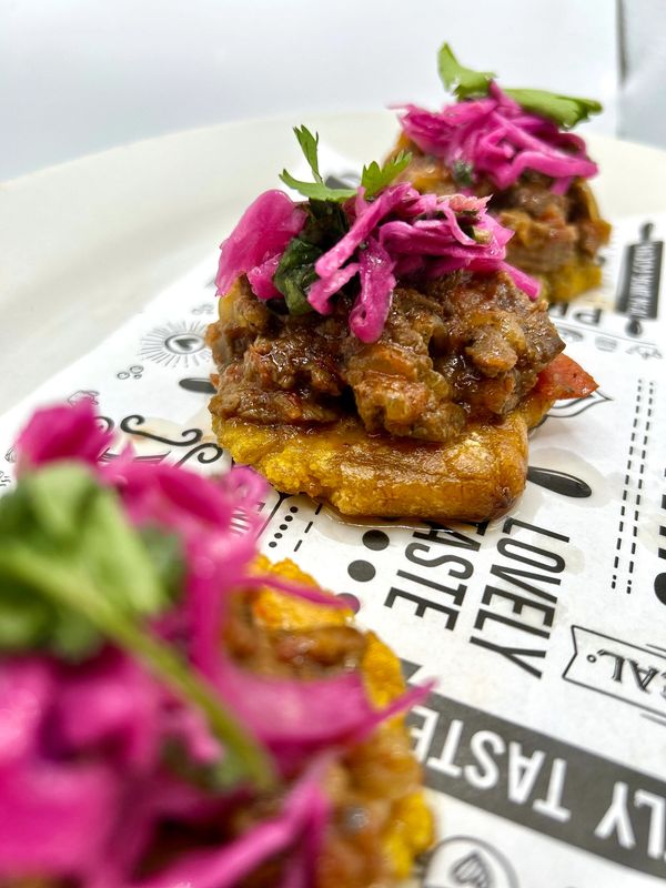 Loaded tostones with seasoned beef, red cabbage salad and cilantro for garnish