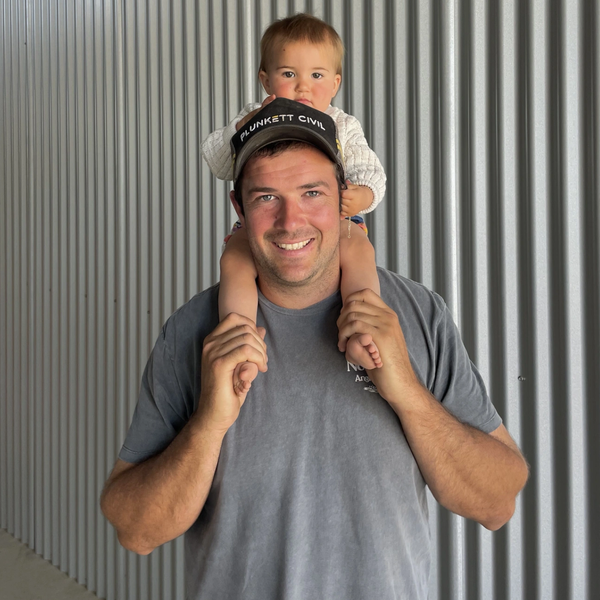 Man carrying child on shoulders, smiling at camera.
