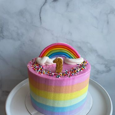 Rainbow ombre buttercream smash cake with a fondant rainbow and 1 on top. 