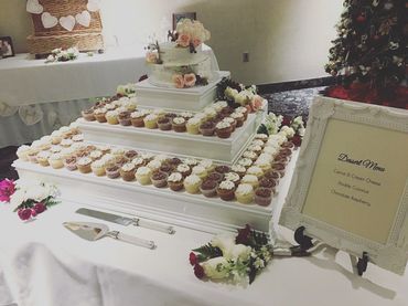 2 tier semi naked buttercream cake with sugar flowers, surrounded by mini cupcakes. 