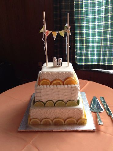 3 tier cake with buttercream piping and orange, lemon and lime slices around the sides. 