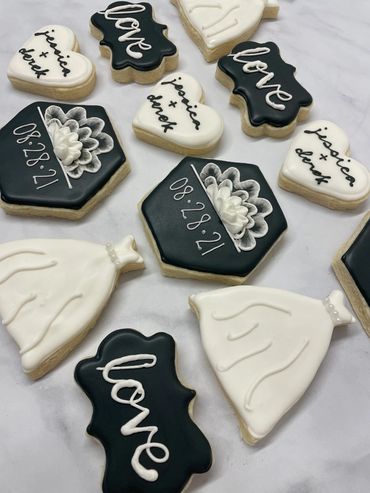 Elegant black and white theme sugar cookies with dresses and a wedding date. 
