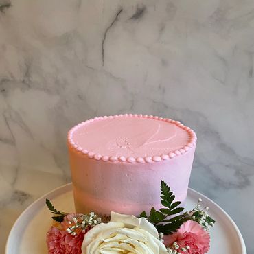 Pink buttercream smash cake with real florals around the front. 