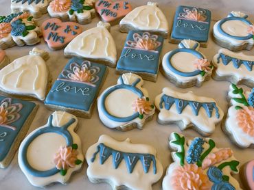 Blue and pink theme engagement cookies with dresses, rings and flowers. 