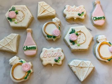 Champagne, rings, and greenery on sugar cookies to celebrate an engagement. 