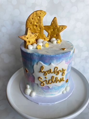 A blue and pink ombre buttercream cake with sugar cookie gold moon and stars. 