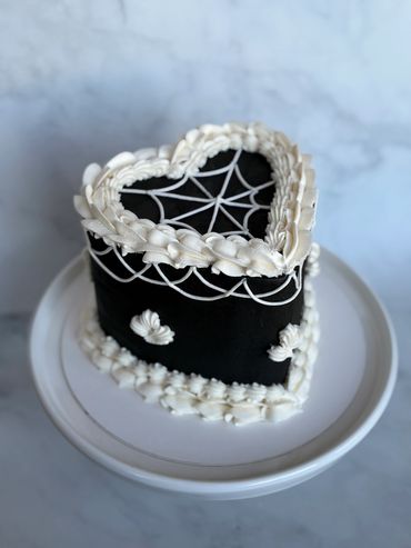 Black heart shape vintage cake with white spiderweb piping. 