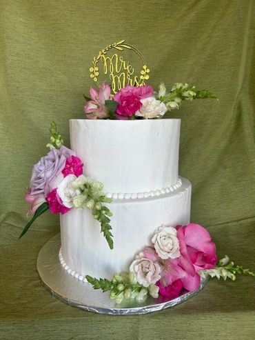 2 tier white buttercream cake with acrylic topper and fresh pink and white flowers. 