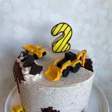 Construction theme kid's birthday cake with Oreo buttercream, chocolate drip and toys on top. 