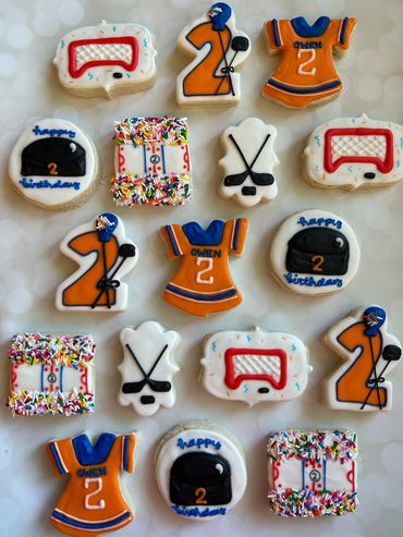 Oilers/hockey themed birthday cookies including a jersey, puck, and net. 