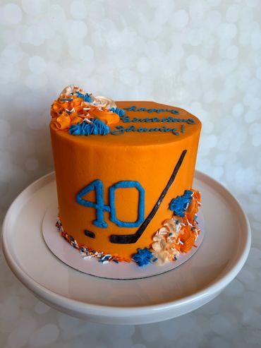 Hockey theme cake with Oilers colors and fondant hockey stick. 
