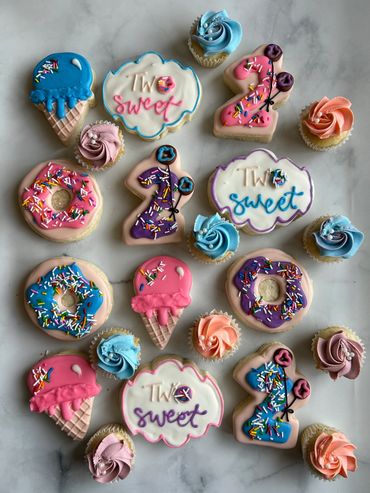 Two Sweet decorated sugar cookies with ice cream and sprinkle donuts. 