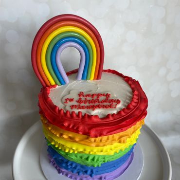 Buttercream rainbow ruffle kids birthday cake with fondant rainbow on top. 