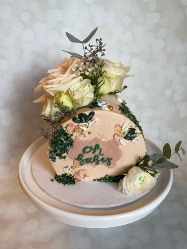 An on-side round cake with white and green flowers and buttercream texture. 
