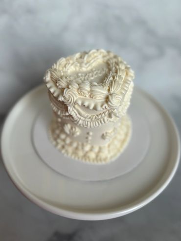 A white vintage heart cake with piping. 