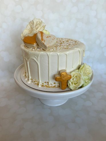 A white buttercream cake with a white drip and gold details. 