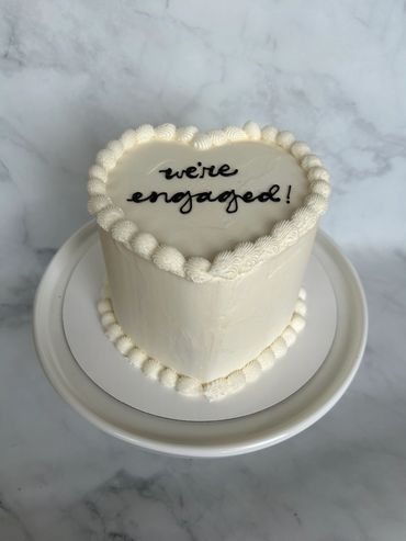 A simple white buttercream heart with white piping. 