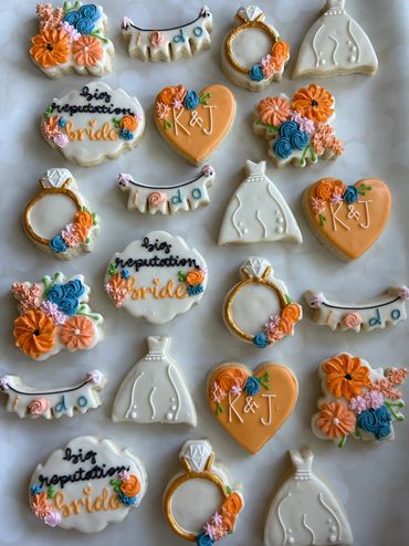 Decorative wedding-themed cookies shaped like rings, dresses, hearts, and flowers.
